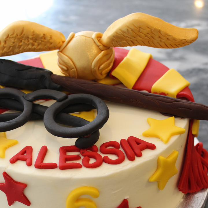 A decorated  cake with Harry Potter themed decorations, including a golden snitch, Harry&