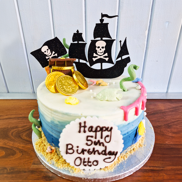 Pirate-themed birthday cake with ship topper and &